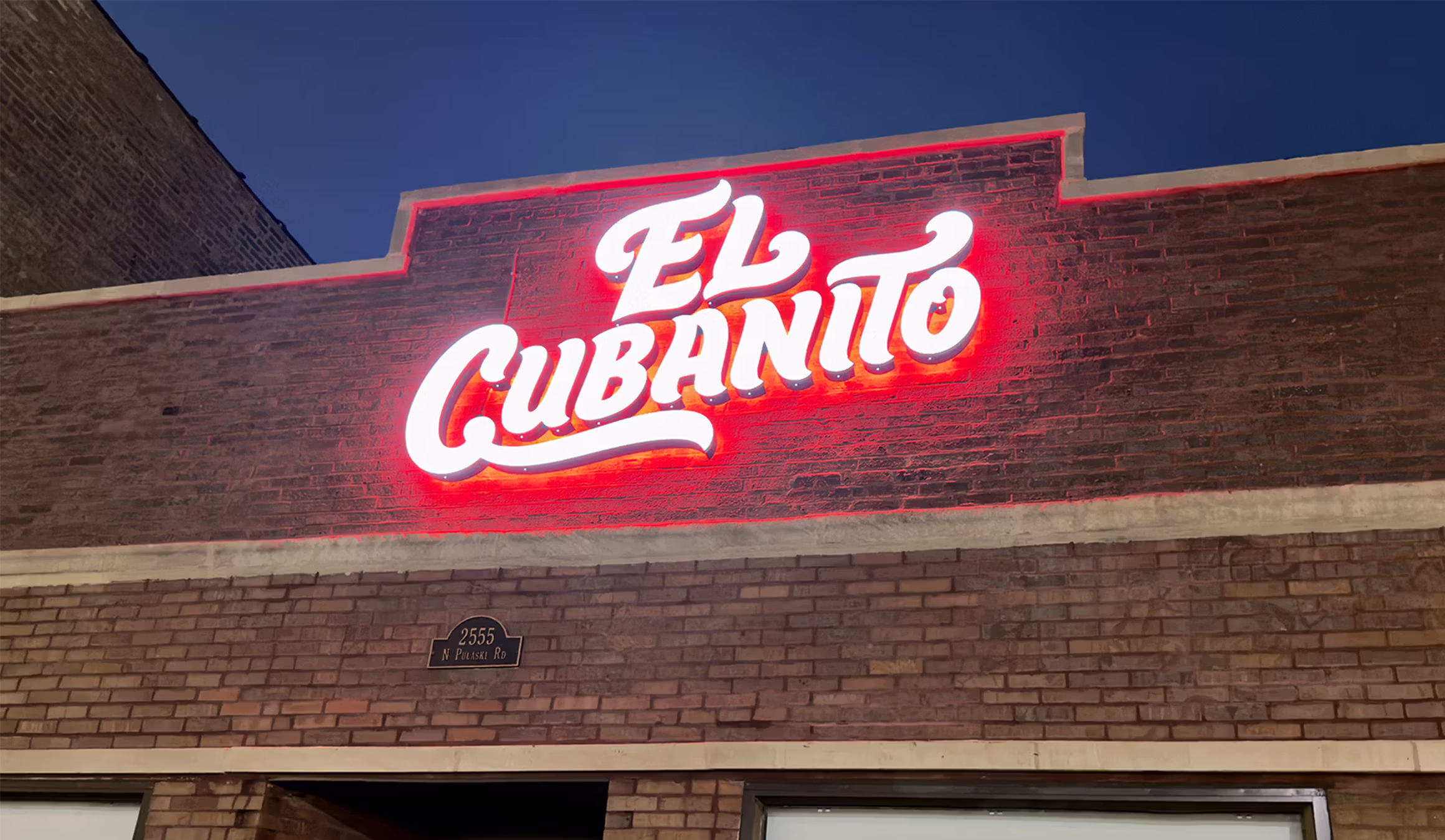 Illuminated El Cubanito storefront sign on a brick building in Chicago